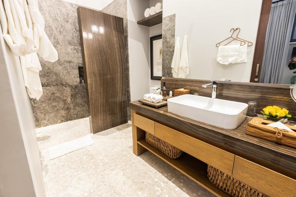 A modern bathroom with a large mirror, a white sink, and a wooden vanity.