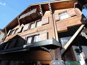Ein mehrstöckiges Holzhaus mit Balkonen, großen Fenstern und einem Schild, auf dem 'Blaue Haus' steht.