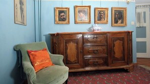 Um quarto com uma poltrona verde, um armário de madeira com várias gavetas e um tapete estampado.