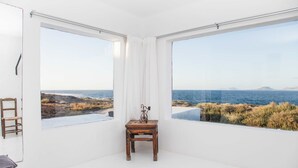 Una habitación con ventanas amplias, una pequeña mesa de madera y una silla.