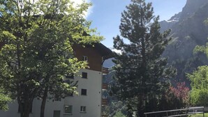 Rakennus, jossa on useita ikkunoita, ja sen ympärillä on vehreää kasvillisuutta ja kirkas taivas.