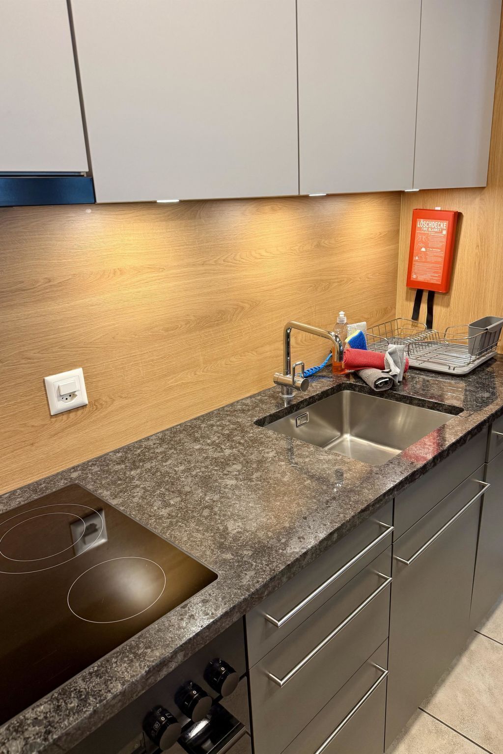 Et køkken med en granitbordplade, stålvask og en integreret kogeplade.