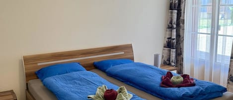 A double bed with a wooden frame, two pillows, and a blue blanket.