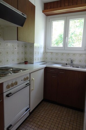 A kitchen with a stove, oven, and a window above the sink. - Leuca 31 # 2-bed apartment, Dusche, WC 2-Bettwohnung, Dusche, WC by Interhome (Leukerbad)