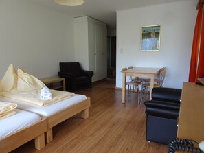 Ein Zimmer mit einem Bett, einem Sessel, einem Tisch und einem Schreibtisch.