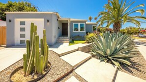 Een modern huis met een terras, cactussen en een palmboom.
