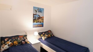 Una camera da letto con due letti singoli, un comodino con lampada e un quadro appeso al muro.