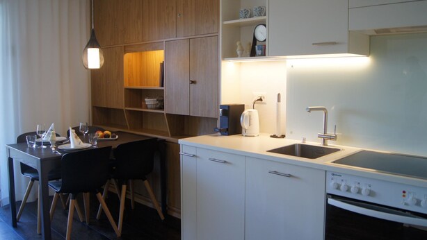 Una cucina moderna con mobili bianchi, forno integrato e zona pranzo con tavolo e sedie.