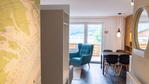 Una stanza con una mappa appesa al muro, una sedia blu, un tavolo da pranzo con sedie e un grande specchio.
