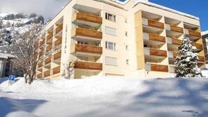Un hotel a più piani con balconi, un cartello per il parcheggio e un paesaggio innevato.