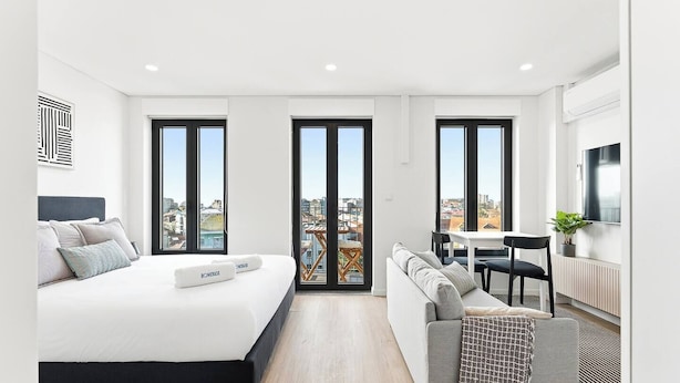 Une chambre d’hôtel moderne équipée d’un grand lit, d’un canapé, d’une table à manger et d’un téléviseur.