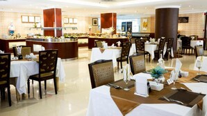 A hotel dining area with multiple tables, chairs, and a buffet setup. - Junior Twin Peaceful Stay in Millnia (Riyadh)