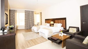 A hotel room with two beds, a desk, a coffee table, a sofa, and a TV. - Junior Twin Peaceful Stay in Millnia (Riyadh)