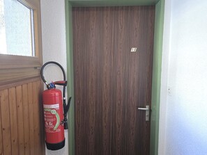 Una puerta de madera con marco verde y un extintor montado en la pared a la izquierda.