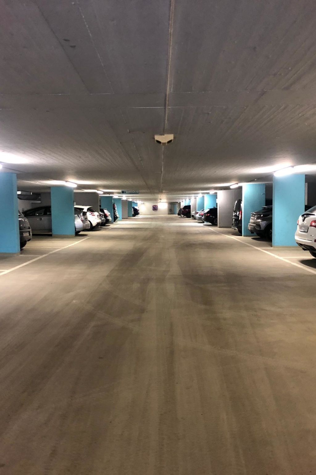 A multi-level parking garage with concrete floors and blue pillars.