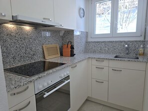 Una cocina con estufa integrada, un lavamanos y una ventana con vistas a árboles.