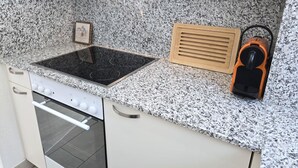 Ett kök med en bänkskiva i granit, en inbyggd spis och en träbeklädd ventilationskåpa.