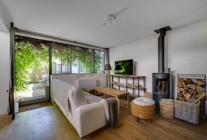 Ein modernes Wohnzimmer mit einer Couch, einem Fernseher, einem Kamin und einem großen Fenster.