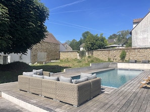Ein Schwimmbad mit Holzterrasse und Korbmöbeln.