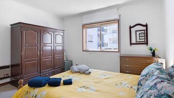 Un dormitorio con cama, armario, cómoda, ventana y espejo.