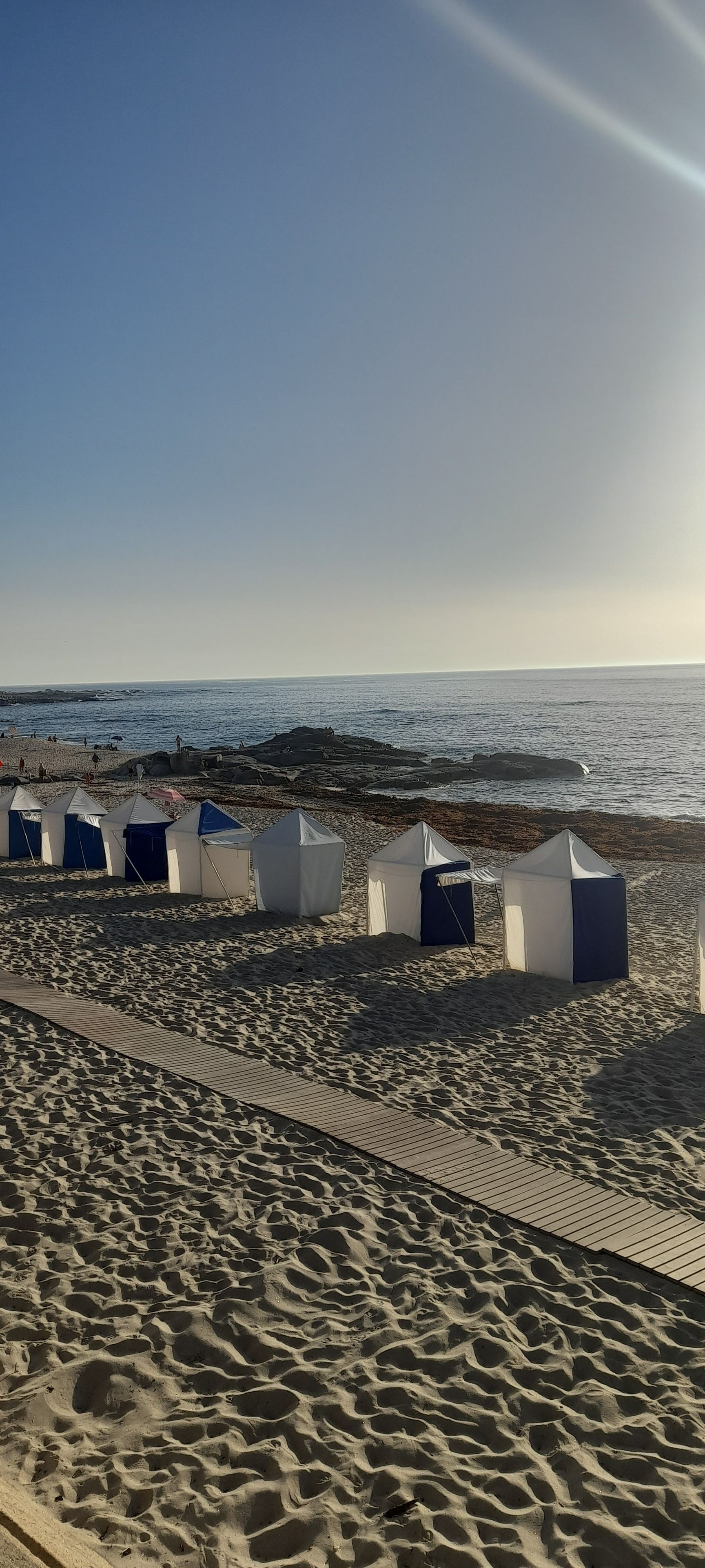 A beach with tents and a rocky shoreline.