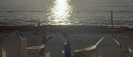 Una playa con tres tiendas pequeñas y una terraza de madera.