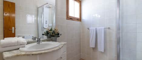 Une salle de bain avec un lavabo, un miroir, une douche et une fenêtre.