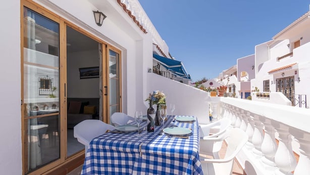 A balcony with a checkered tablecloth, white chairs, and a dining setup. - Port Royale 75 - Two Bed (Los Cristianos)
