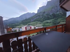 A balcony with a table and chairs overlooking a mountainous landscape with buildings in the distance. - Ambassador B33 # 4-bed apartment, Dusche und Bad, WC by Interhome (Leukerbad)