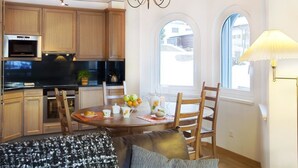 Una cocina moderna con armarios de madera, horno empotrado y comedor con una mesa dispuesta para dos personas.