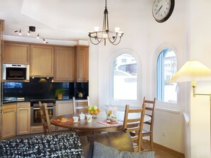 Eine moderne Küche mit Holzausstattung, einem eingebauten Backofen und einem Essbereich mit gedecktem Tisch für zwei Personen.