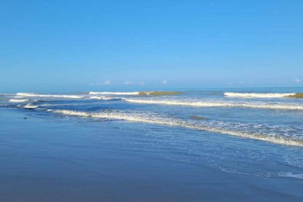 A beach with waves and a clear sky.