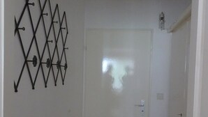A hallway with a white door, a wall-mounted decorative metal piece, and a light fixture. - Fortuna 201 # 4-bed apartment, Dusche, WC 4-Bettwohnung, Dusche, WC by Interhome (Leukerbad)