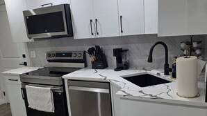 Een moderne keuken met witte kasten, roestvrijstalen apparatuur, een ingebouwde magnetron en een koffiezetapparaat.
