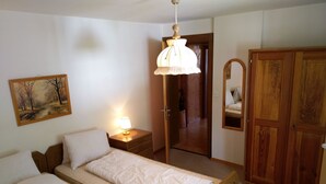 Quarto com duas camas, um abajur, um guarda-roupa de madeira e um quadro na parede.