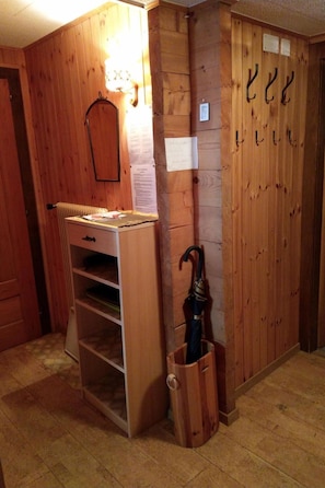 A wooden room with a desk, shelves, and an umbrella in a wooden basket. - Gassenboden 31 # 4-bed apartment, Bad, WC 4-Bettwohnung, Bad, WC by Interhome (Leukerbad)