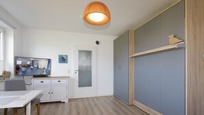 Una stanza con un tavolo da pranzo, una televisione, un armadio e una porta con vetro smerigliato.