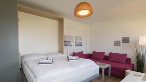 Una camera da letto con un letto, un divano rosso, un tavolino e una lampada a sospensione.