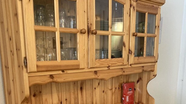 Un mueble de madera con varios cajones y un compartimento superior con puerta de cristal.
