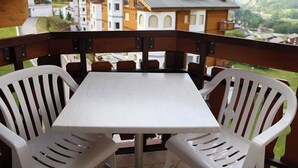 Varanda com mesa e cadeiras com vista para uma paisagem montanhosa.