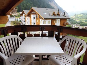Ein Balkon mit Tisch und Stühlen mit Blick auf eine gebirgige Landschaft.