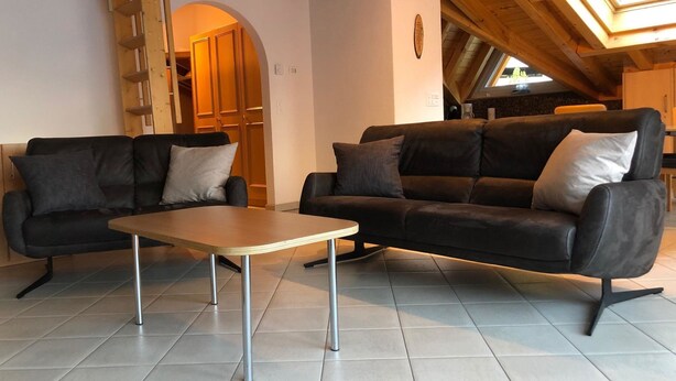 Uma sala de estar moderna com dois sofás, uma mesa de centro e teto de madeira.