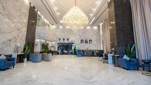 Um hall amplo com um lustre imponente, paredes de mármore e áreas de estar modernas.