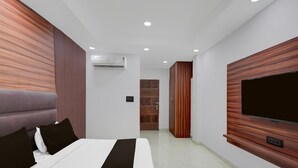 A modern hotel room with a large bed, a flat-screen TV mounted on the wall, and a built-in wardrobe. - Suite Budha Tower (Noida)