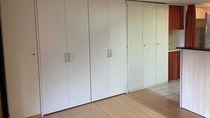 A room with a large wardrobe, a kitchen area, and a wooden floor. - Domino 15 # 2-bed apartment, Dusche, WC 2-bed apartment, Dusche, WC by Interhome (Leukerbad)