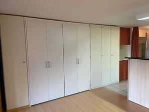 A room with a large wardrobe, a kitchen area, and a wooden floor. - Domino 15 # 2-bed apartment, Dusche, WC 2-bed apartment, Dusche, WC by Interhome (Leukerbad)