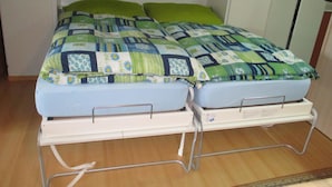 A twin bed with a quilt, a bedside table, and a wall-mounted shelf. - Domino 15 # 2-bed apartment, Dusche, WC 2-bed apartment, Dusche, WC by Interhome (Leukerbad)