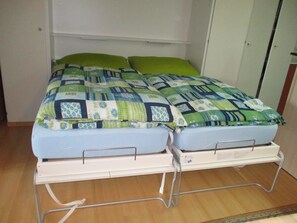A twin bed with a quilt, a bedside table, and a wall-mounted shelf. - Domino 15 # 2-bed apartment, Dusche, WC 2-bed apartment, Dusche, WC by Interhome (Leukerbad)