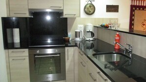 A kitchen with stainless steel appliances, a coffee maker, and a sink. - Domino 15 # 2-bed apartment, Dusche, WC 2-bed apartment, Dusche, WC by Interhome (Leukerbad)