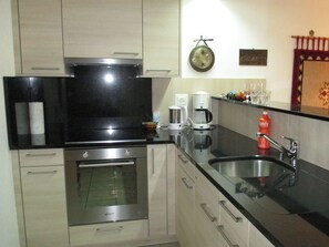 A kitchen with stainless steel appliances, a coffee maker, and a sink. - Domino 15 # 2-bed apartment, Dusche, WC 2-bed apartment, Dusche, WC by Interhome (Leukerbad)